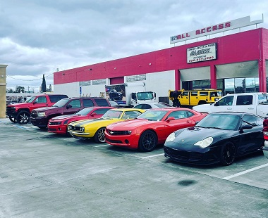 spacious yet full parking lot at All Access Automotive in Fresno, California. There is a lineup of different vehicles, including two Chevy Camaros